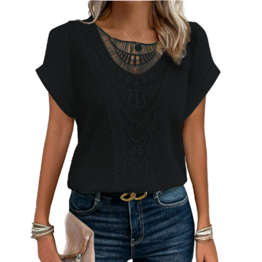 Femme portant le haut d’été Kester noir, coupe ample avec manches courtes et détail motif crochet ajouré au col, style tendance et léger, associé à un jean bleu et une pochette.