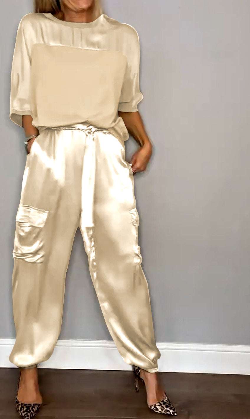 Une tenue élégante composée d'un haut satiné beige et d'un pantalon fluide de couleur crème avec des poches, porté avec des escarpins à motif léopard.