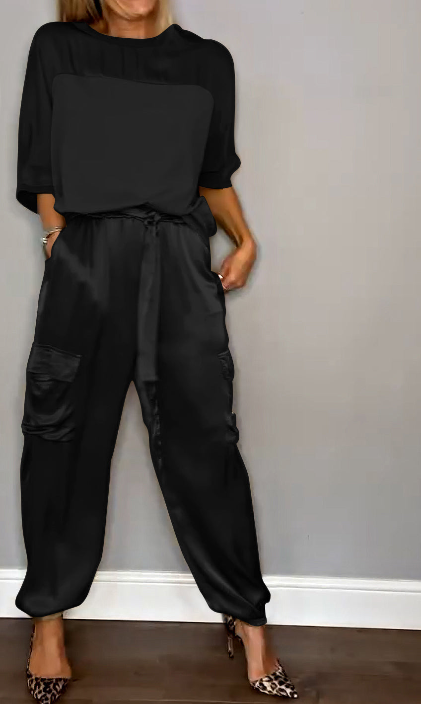 Un ensemble élégant composé d'un haut satiné noir et d'un pantalon fluide avec des poches, porté avec des escarpins à motif léopard.