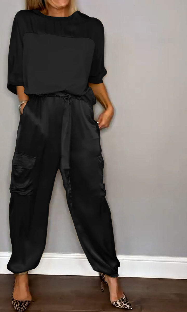 Un ensemble élégant composé d'un haut satiné noir et d'un pantalon fluide avec des poches, porté avec des escarpins à motif léopard.