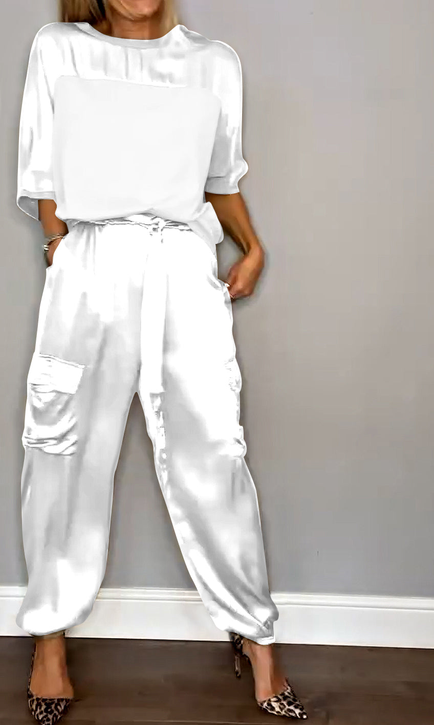 Une tenue élégante composée d'un haut en satin blanc et d'un pantalon fluide avec des poches, porté avec des escarpins à motif léopard.