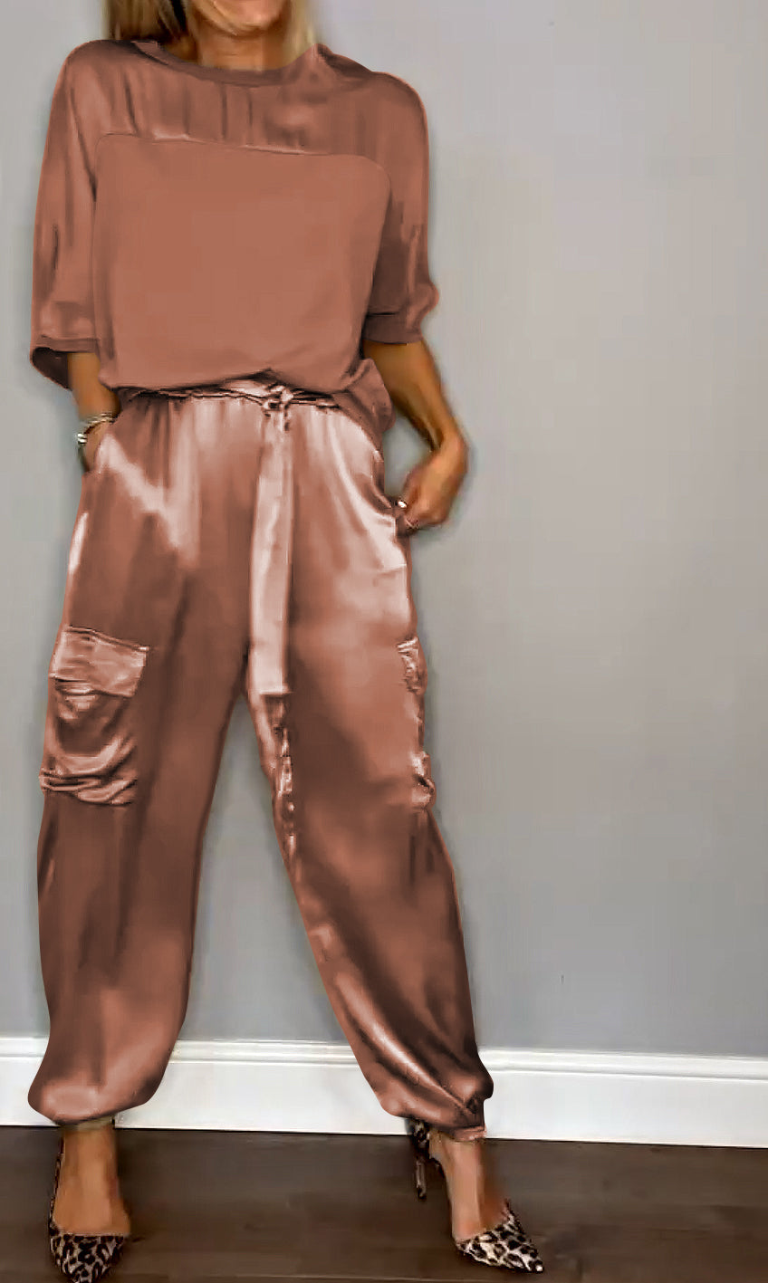 Un ensemble raffiné composé d'un haut satiné rose et d'un pantalon fluide avec des poches, porté avec des escarpins à motif léopard.
