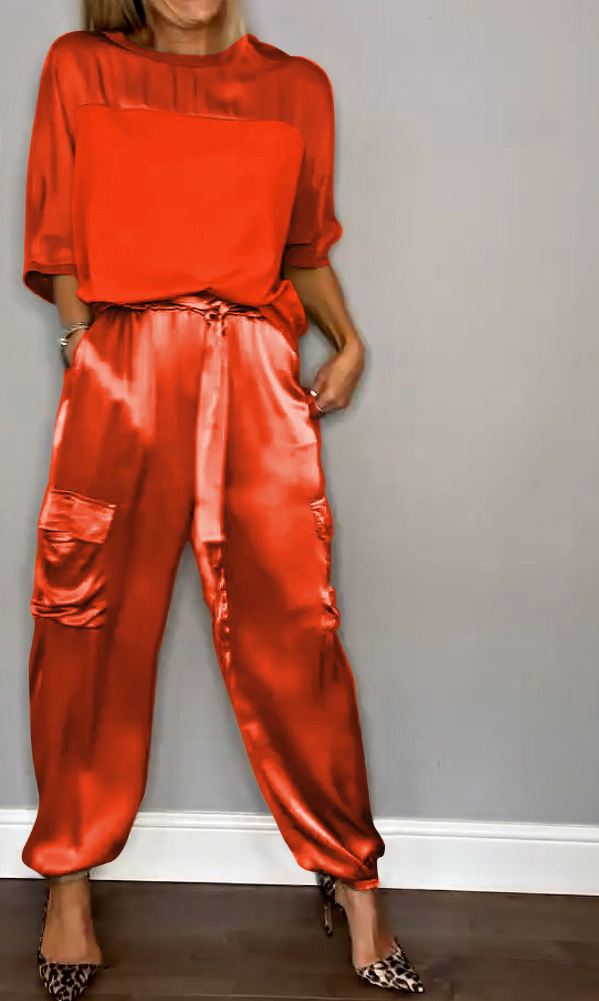 Une tenue élégante composée d'un haut en satin rouge et d'un pantalon fluide à taille élastique avec des poches, porté avec des escarpins à motif léopard.