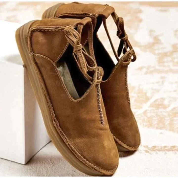 Chaussures d’automne pour femme en cuir suédé marron camel, avec bout arrondi, coutures apparentes et lien décoratif sur le côté, présentées sur un fond clair pour un style moderne et naturel.