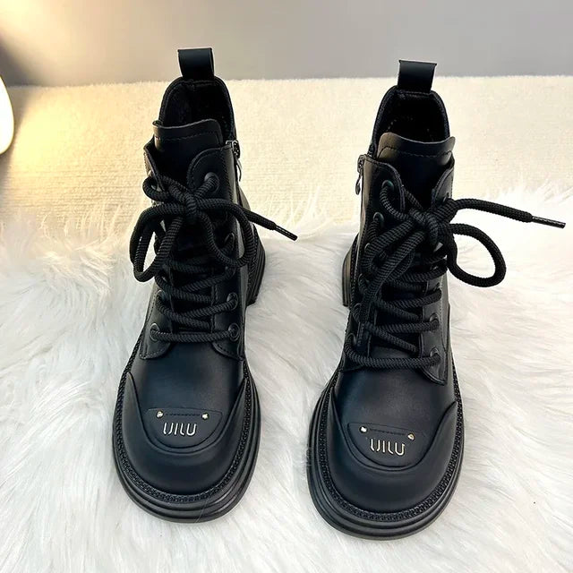 Bottines noires pour femme avec des lacets noirs robustes, présentant une semelle épaisse et une partie avant distinctive, avec un design moderne et tendance, idéal pour les saisons froides.