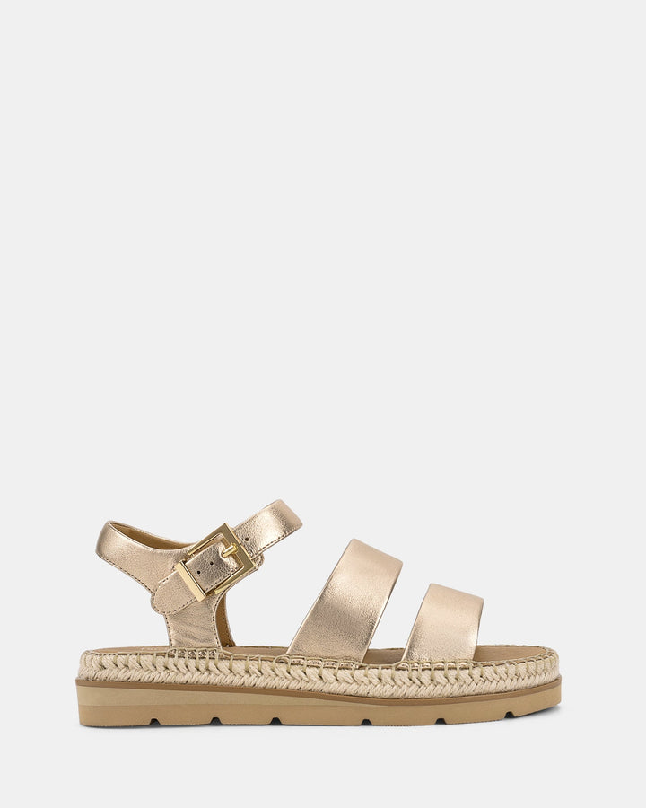 Vue latérale des sandales avec des lanières dorées et une boucle réglable, dotées d'une semelle tressée pour un look estival chic.