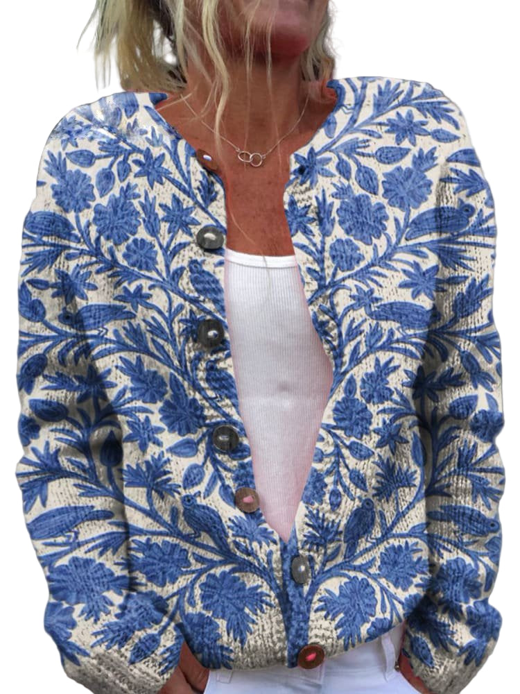 Femme portant un cardigan en maille clair décoré de broderies florales bleues, avec une coupe moderne et des boutons sur le devant, posant en extérieur.