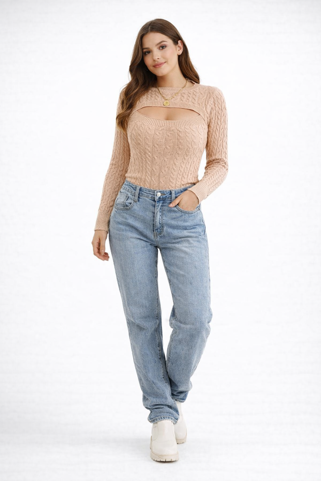 Haut tricoté à manches longues pour femme, couleur beige, avec un décolleté découpé moderne et une texture en tricot torsadé. Le modèle est porté avec un jean bleu clair et des bottines blanches, créant un look décontracté et tendance, parfait pour un style chic et casual.