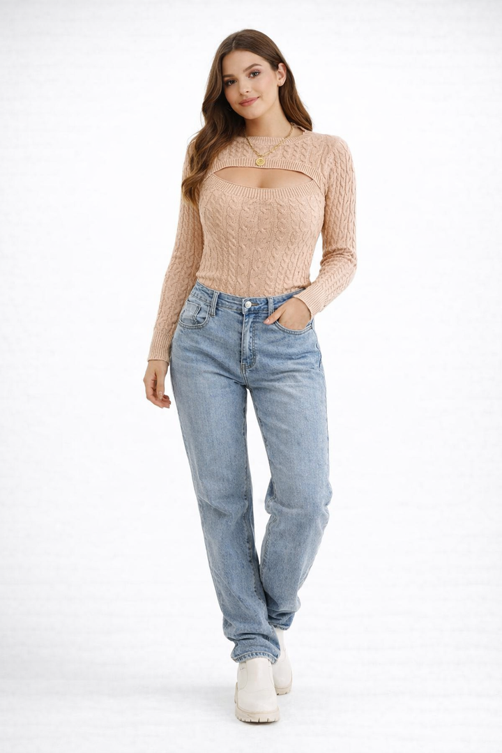 Haut tricoté à manches longues pour femme, couleur beige, avec un décolleté découpé moderne et une texture en tricot torsadé. Le modèle est porté avec un jean bleu clair et des bottines blanches, créant un look décontracté et tendance, parfait pour un style chic et casual.