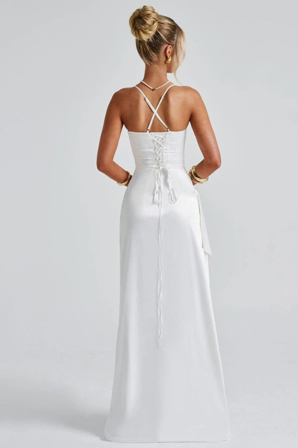 Vue arrière de la robe maxi satinée blanche, avec un dos nu délicatement lacé pour un ajustement parfait et un look séduisant. Cette robe offre un style raffiné et sexy, idéale pour une soirée élégante ou une fête, tout en mettant en valeur la silhouette avec son design sophistiqué et sa fente haute.