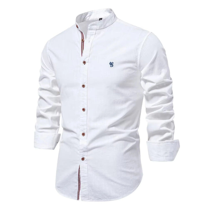 Cette chemise blanche à manches longues présente un col Mao élégant et des boutons en bois contrastés. Elle est ornée d'un petit logo bleu brodé sur la poitrine, offrant un look à la fois raffiné et décontracté, parfait pour les journées fraîches.