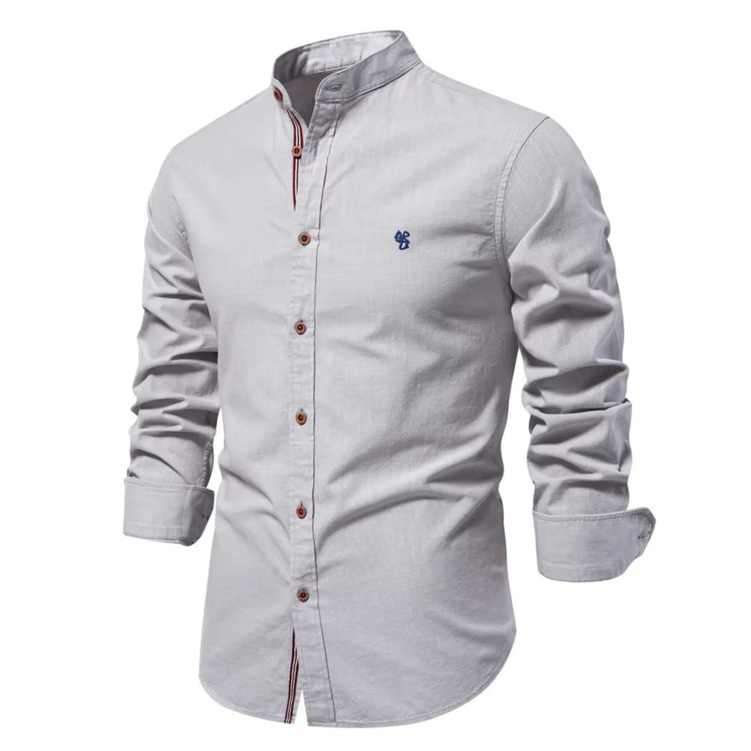 Cette chemise à manches longues de couleur grise claire présente un col Mao élégant, des boutons en bois contrastés et un petit logo brodé sur la poitrine. Parfaite pour un look à la fois chic et décontracté, elle est idéale pour les journées fraîches.