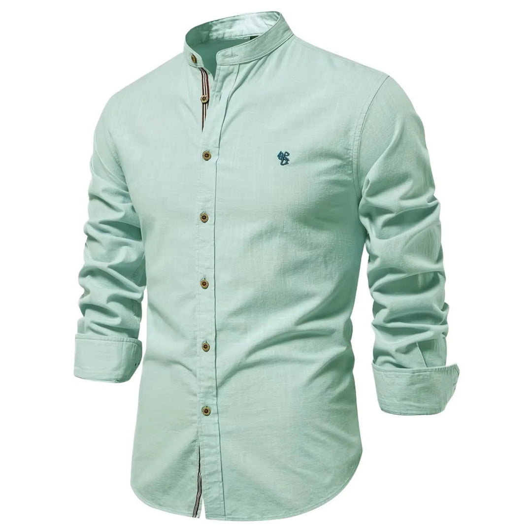Cette chemise à manches longues de couleur vert menthe présente un col Mao, des boutons en bois contrastés et un petit logo brodé sur la poitrine. Idéale pour un look frais et élégant, elle combine confort et style pour un look décontracté et moderne.