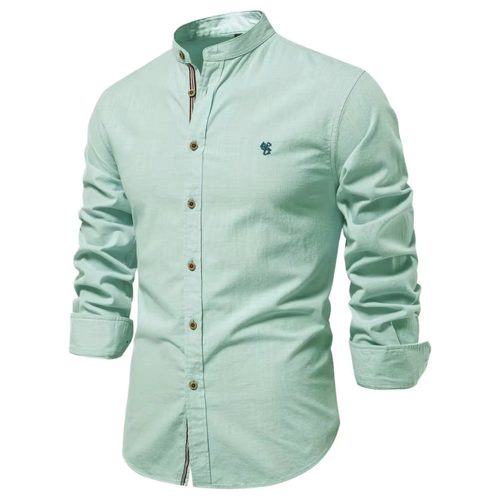 Cette chemise à manches longues de couleur vert menthe présente un col Mao, des boutons en bois contrastés et un petit logo brodé sur la poitrine. Idéale pour un look frais et élégant, elle combine confort et style pour un look décontracté et moderne.