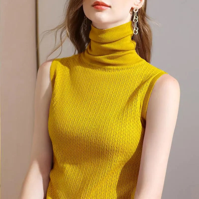Haut sans manches de couleur jaune moutarde avec un col roulé, parfait pour un look moderne et lumineux. Ce modèle élégant est porté avec des boucles d'oreilles tendance, ajoutant une touche de sophistication à la tenue.