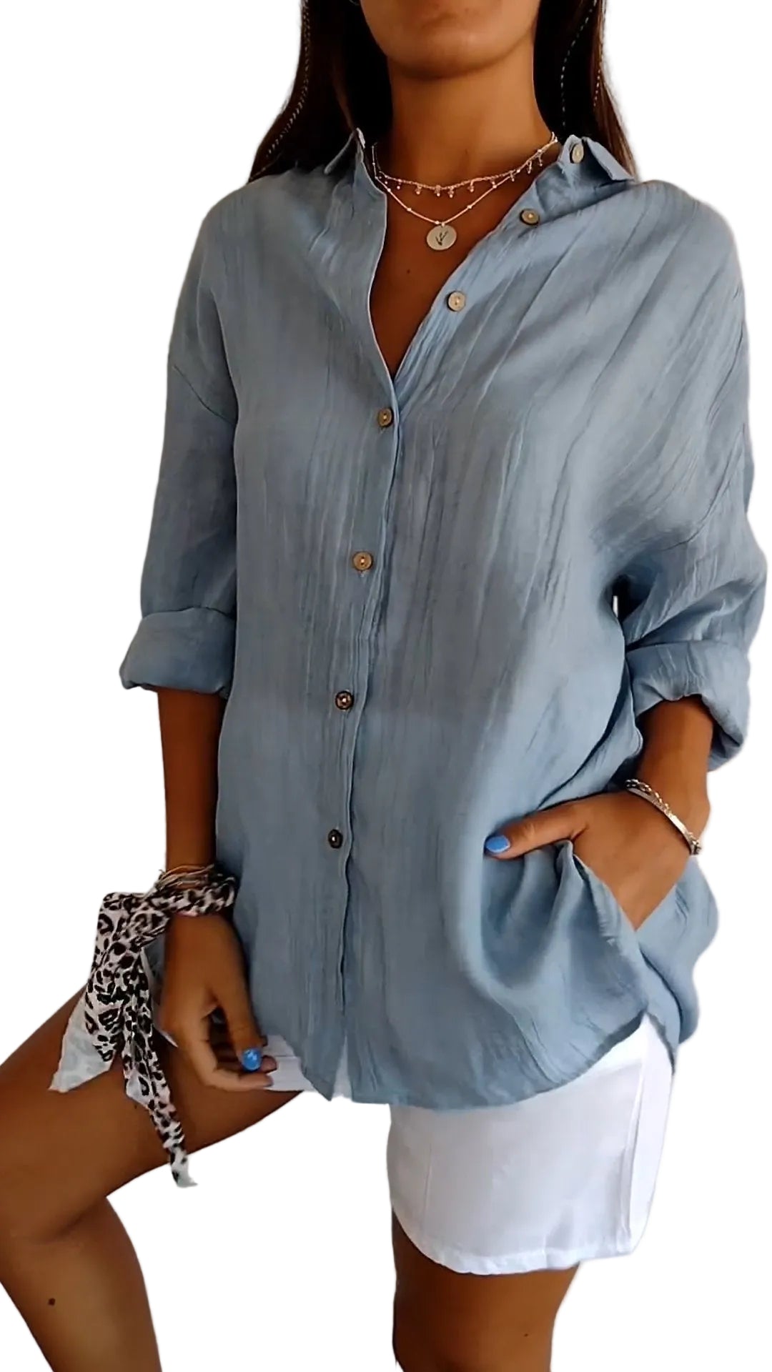 Chemise plissée pour femme  bleu clair, coupe ample avec col ouvert et manches retroussées, boutonnage devant, portée avec un short blanc.