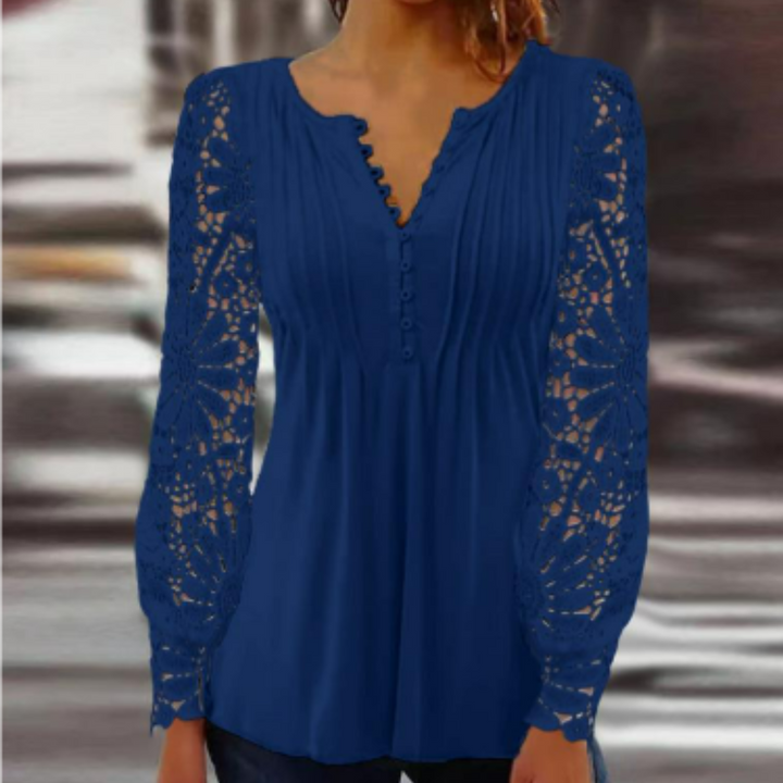 Une blouse élégante en bleu, avec des manches longues en dentelle délicate. Le décolleté en V et les boutons ajoutent une touche féminine et moderne, parfaite pour un look chic et décontracté.