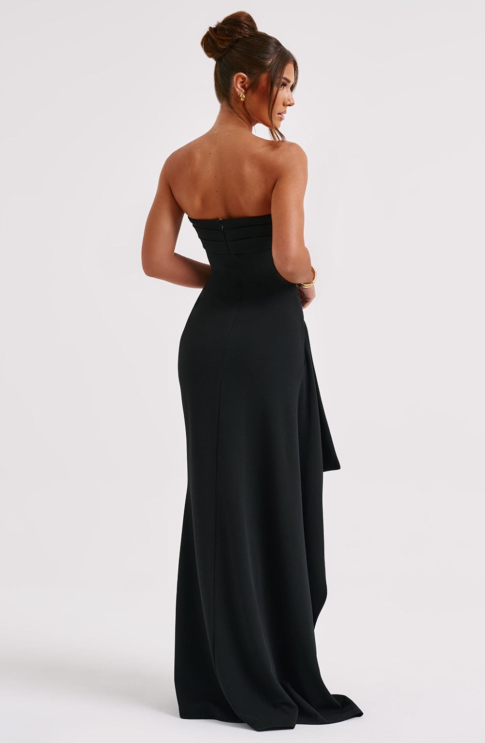 Vue arrière de la robe élégante Malika, idéale pour vos soirées et événements spéciaux. Cette robe noire sans bretelles, au design épuré, met en valeur la silhouette avec sa coupe ajustée et son drapé élégant. Sa fente audacieuse sur le côté ajoute une touche de sophistication, parfaite pour un look glamour et raffiné.
