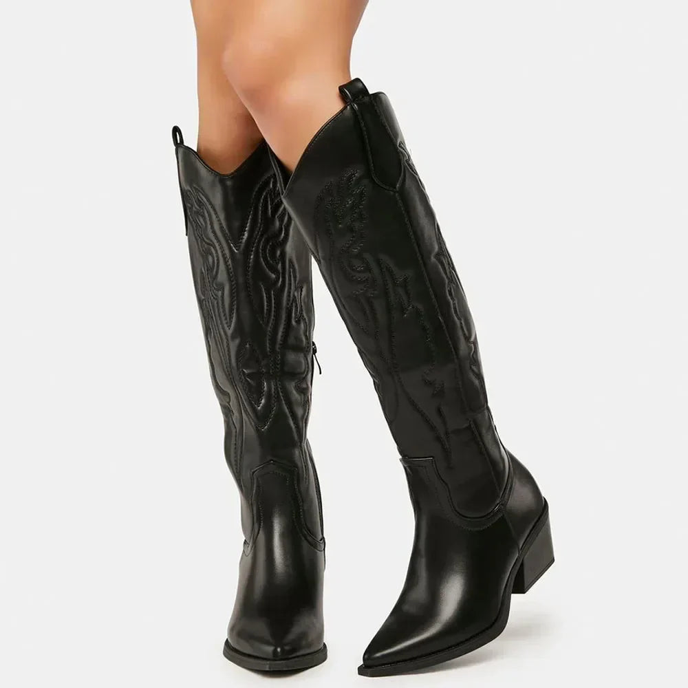 Bottes western noires à talons carrés pour femme, avec des détails de coutures décoratives sur toute la tige. La forme pointue à l'avant et la fermeture éclair latérale ajoutent une touche de modernité à ce modèle élégant.