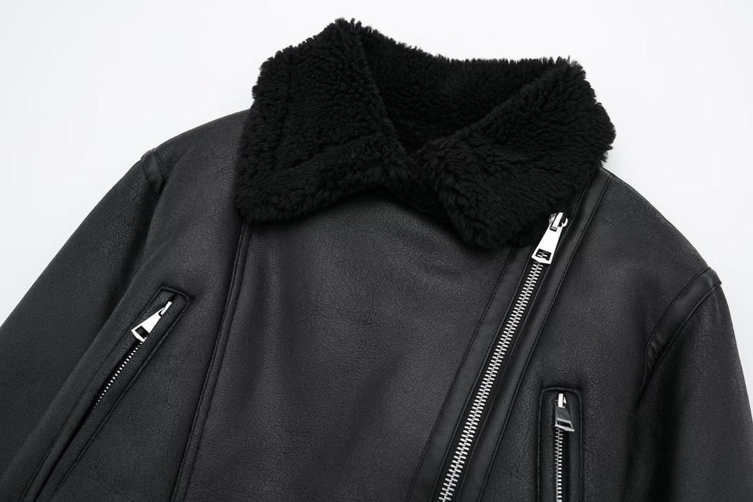 Gros plan sur une veste courte noire pour femme en simili cuir, mettant en valeur le col en fausse fourrure, la fermeture éclair asymétrique et les poches zippées verticales.