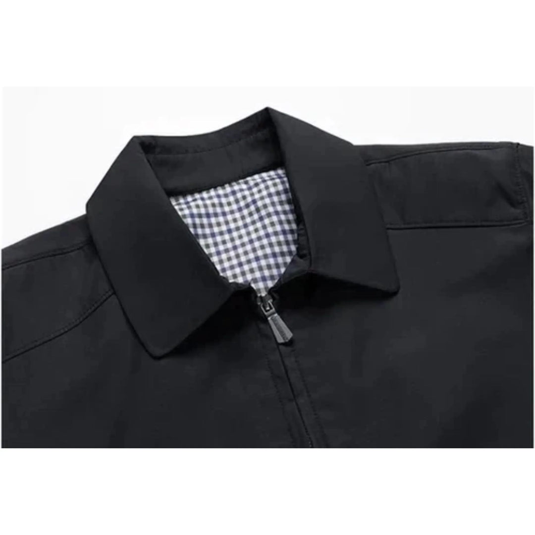 Détail du col du manteau noir, avec une fermeture éclair discrète et une doublure à carreaux bleus et blancs. Ce manteau offre une combinaison élégante de style et de fonctionnalité, idéal pour les journées pluvieuses.