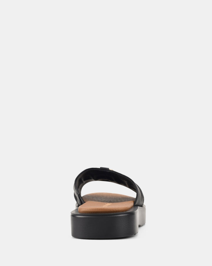 Vue arrière des sandales avec une semelle épaisse et une boucle dorée, offrant un look élégant et une bonne stabilité.