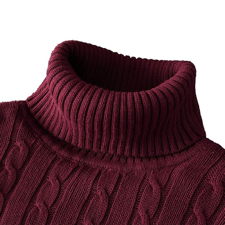 Zoom sur le col roulé d'un pull bordeaux en tricot côtelé avec un motif en torsades.