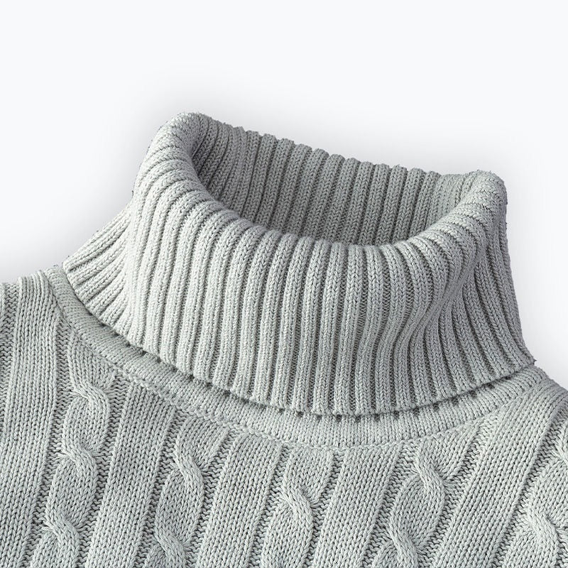 Zoom sur le col roulé d'un pull gris clair en tricot côtelé avec un motif en torsades.