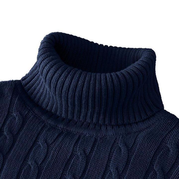 Zoom sur le col roulé d'un pull bleu marine en tricot côtelé avec un motif en torsades.