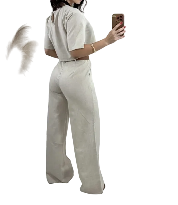 Cet ensemble beige composé d'un pantalon évasé et d'un top à manches courtes offre une coupe élégante et décontractée. Le pantalon présente une taille haute et des détails raffinés, parfait pour un look à la fois chic et confortable.