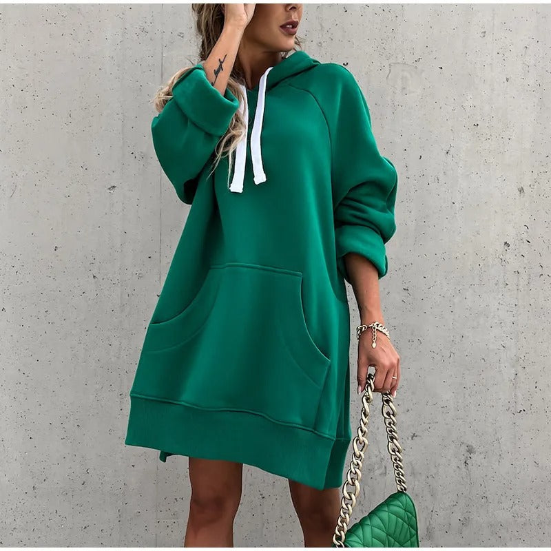 Sweat à capuche oversize vert porté en robe, cordons blancs et grande poche kangourou, manches retroussées, fente latérale, sac à chaîne.