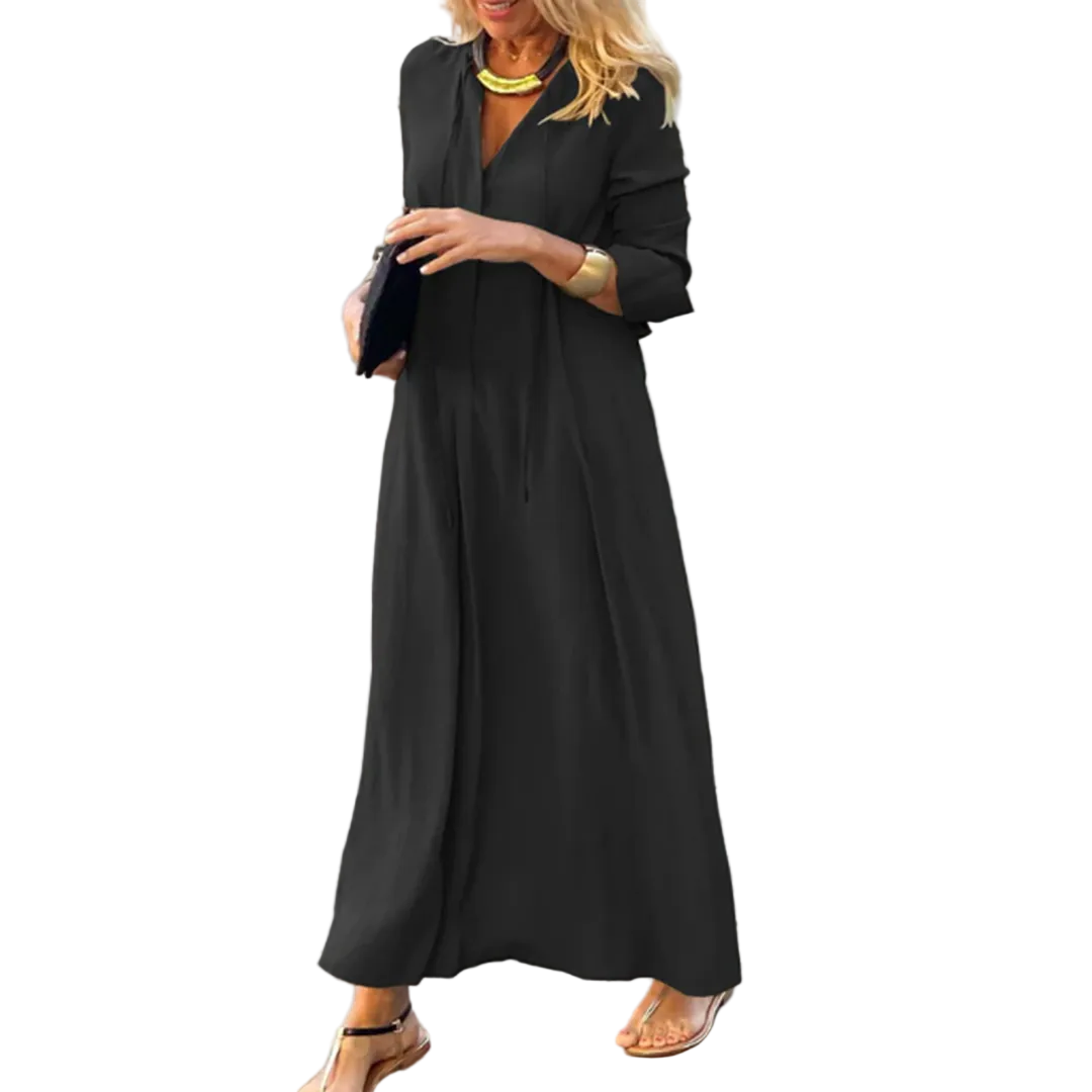 Femme portant la robe maxi d’été Nadège, longue robe noire fluide à manches 3/4 et col en V, coupe ample et élégante, portée avec des sandales et des accessoires dorés  style moderne et chic en extérieur.