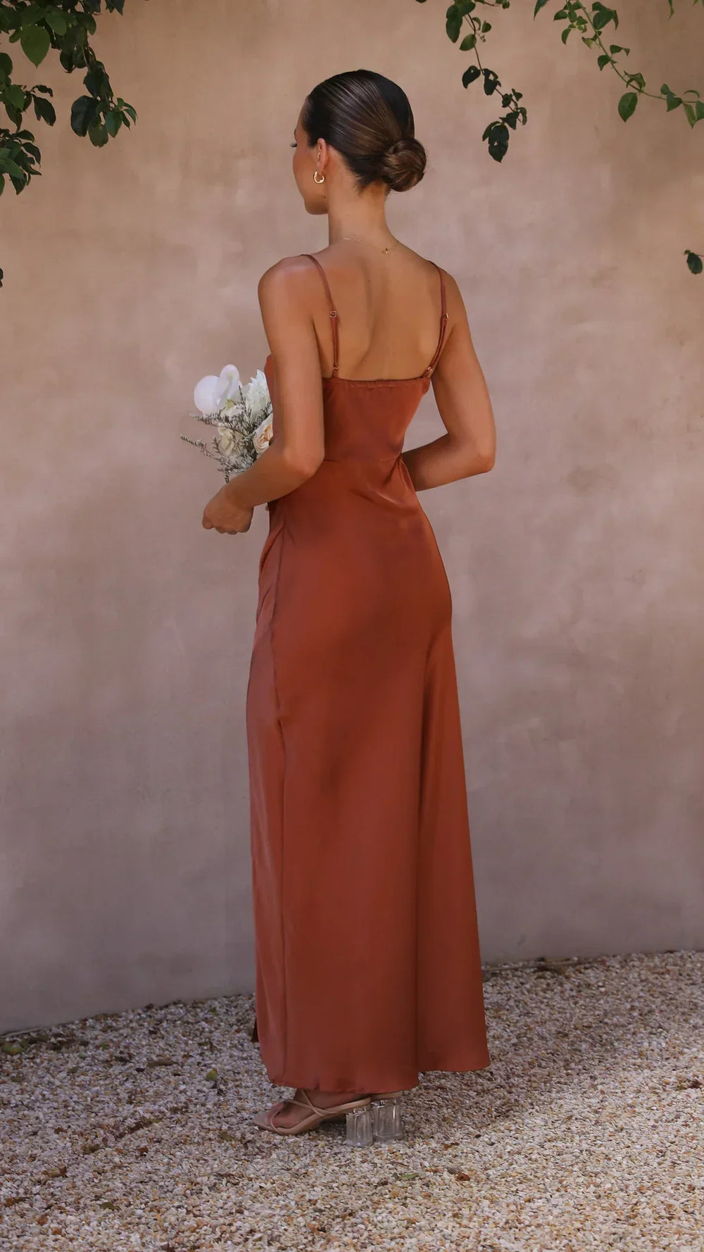 Vue arrière de la robe maxi pour femme, avec des bretelles spaghetti fines et une coupe fluide. La robe, d'une teinte brune élégante, épouse parfaitement la silhouette et offre un look moderne et raffiné. Idéale pour des événements estivaux ou des occasions spéciales, elle combine confort et sophistication.