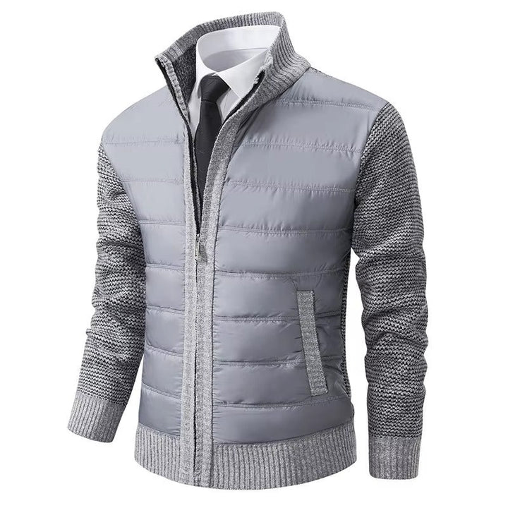 Veste pour homme, avec un corps matelassé gris clair et des manches en tricot gris. Elle dispose d'une fermeture éclair centrale et de poches latérales, alliant confort et style moderne pour un look pratique et élégant.