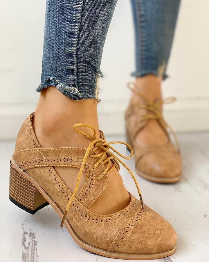 Chaussures camel style Mary Jane rétro à lacets, détails perforés et talon carré effet bois, portées avec un jean sur sol clair, vue de profil.