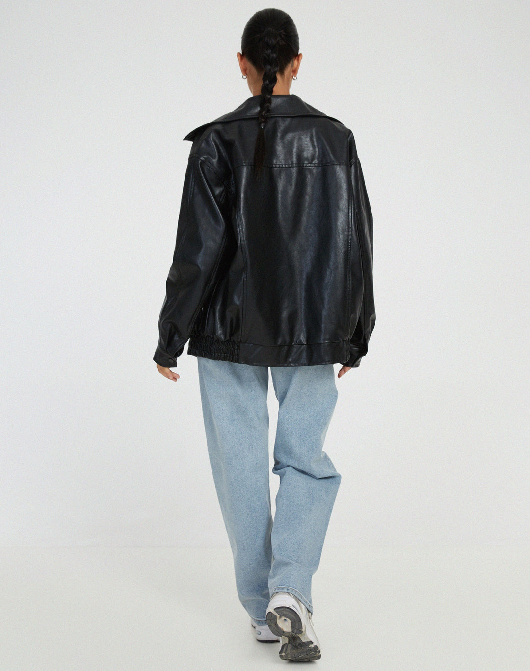 Vue arrière de la veste oversize en PU pour femme, modèle Ombeline. Veste en simili-cuir noir à la coupe ample, portée avec un jean décontracté et des baskets. Un look moderne et stylé, parfait pour l'hiver.