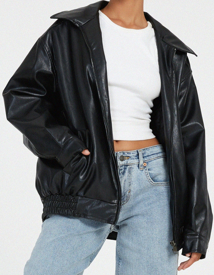 Détail de la veste oversize en PU pour femme, modèle Ombeline. Veste en simili-cuir noir à la coupe ample, fermée par une fermeture éclair, portée avec un t-shirt blanc et un jean décontracté. Un look moderne et confortable, idéal pour l'hiver.