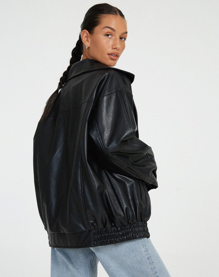 Vue arrière de la veste oversize en PU pour femme, modèle Ombeline. Veste en simili-cuir noir à la coupe ample et taille élastiquée, portée avec un jean décontracté. Un style moderne et confortable, idéal pour l'hiver.