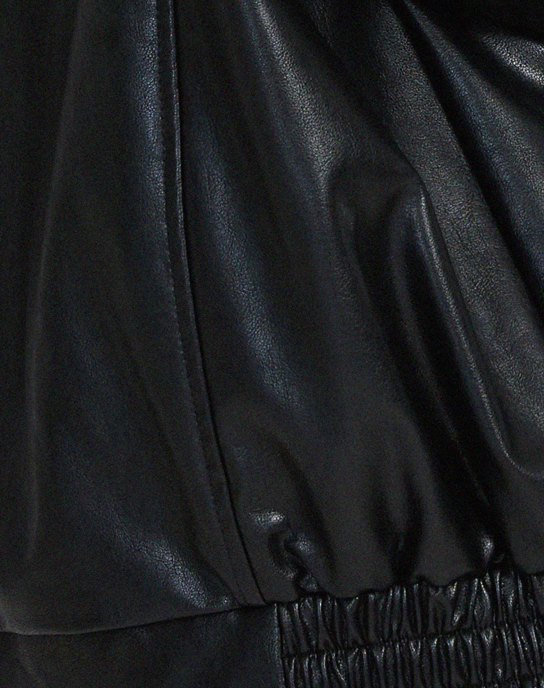 Détail de la veste oversize en PU pour femme, modèle Ombeline. Zoom sur la finition de la taille élastiquée en simili-cuir noir, soulignant le style ample et décontracté de la veste, parfaite pour l'hiver.