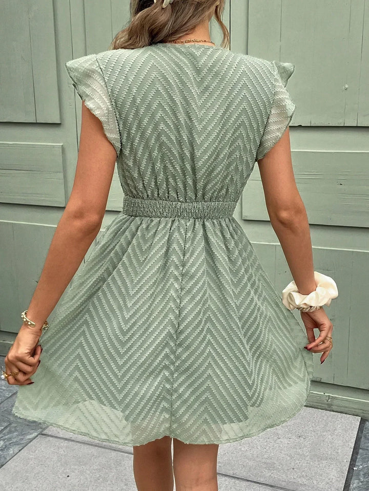 Robe mini d'été à col V pour femme, avec des volants délicats et une taille élastiquée qui offre un ajustement confortable. Son tissu léger à motif chevron et sa coupe fluide en font la pièce parfaite pour un look estival à la fois tendance et féminin