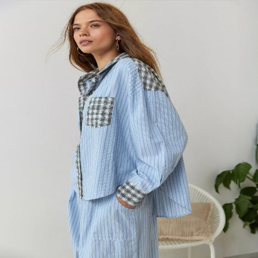 Pyjama pour femme à rayures bleues, avec un haut à manches longues et des détails à carreaux sur les poches et les manches. Le look est à la fois décontracté et élégant, parfait pour une tenue confortable et stylée pour la nuit.