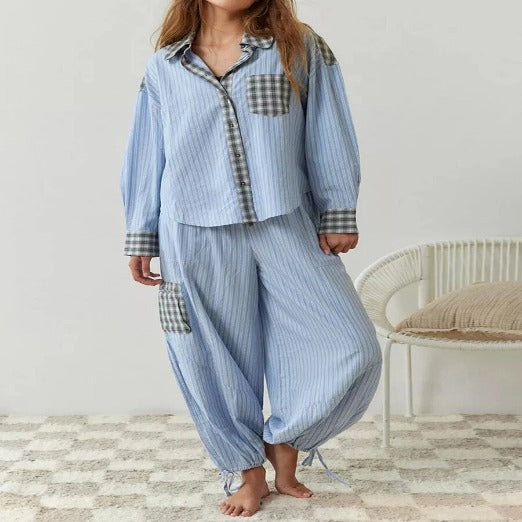 Pyjama pour femme à rayures bleues avec des détails à carreaux sur le haut et les poches. Le pantalon est élastiqué à la taille et aux chevilles, offrant un confort optimal. Le style décontracté mais élégant est parfait pour une tenue nocturne stylée.