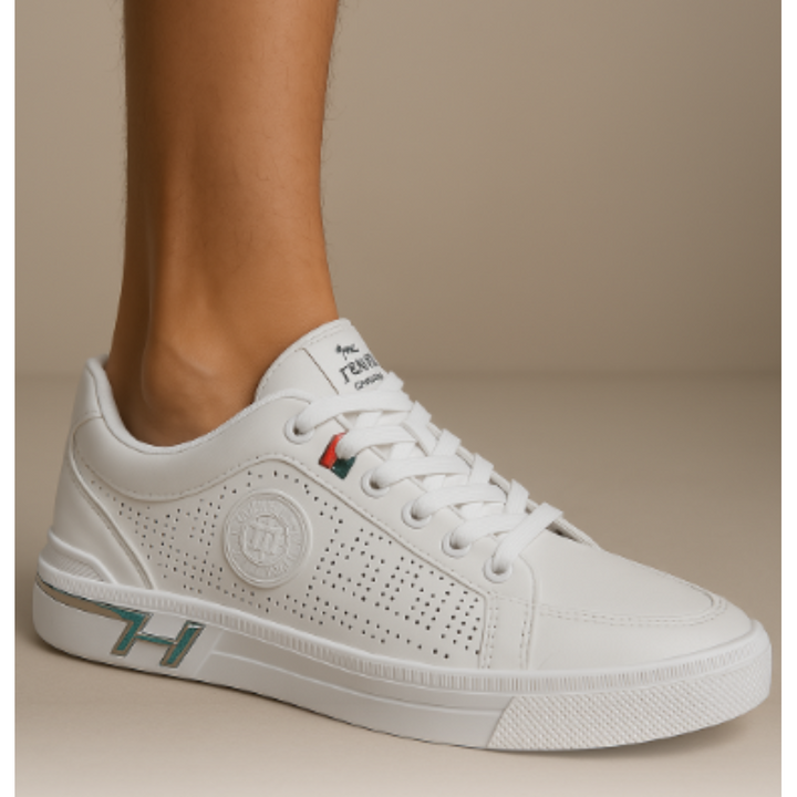 Gros plan des baskets urbaines pour hommes Prosper blanches, style moderne avec lacets, perforations latérales et détails vert/rouge, portées au pied pour mettre en valeur la semelle et la finition élégante.
