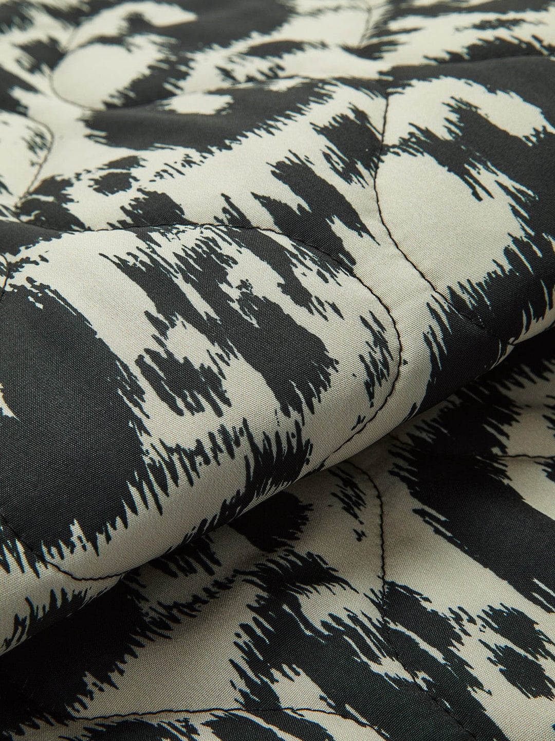 Détail du tissu du manteau ajusté à sequins Prylia pour invitées de mariage, mettant en évidence le motif animalier noir et blanc. Ce zoom montre la texture élégante du tissu, offrant à ce manteau une finition sophistiquée et moderne pour des occasions spéciales.
