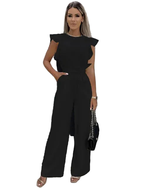 Combinaison noire pour femme avec des manches volantes et une coupe large. Elle présente un design moderne, élégant et raffiné, idéal pour une sortie ou un événement spécial, complétée par une pochette et des sandales.