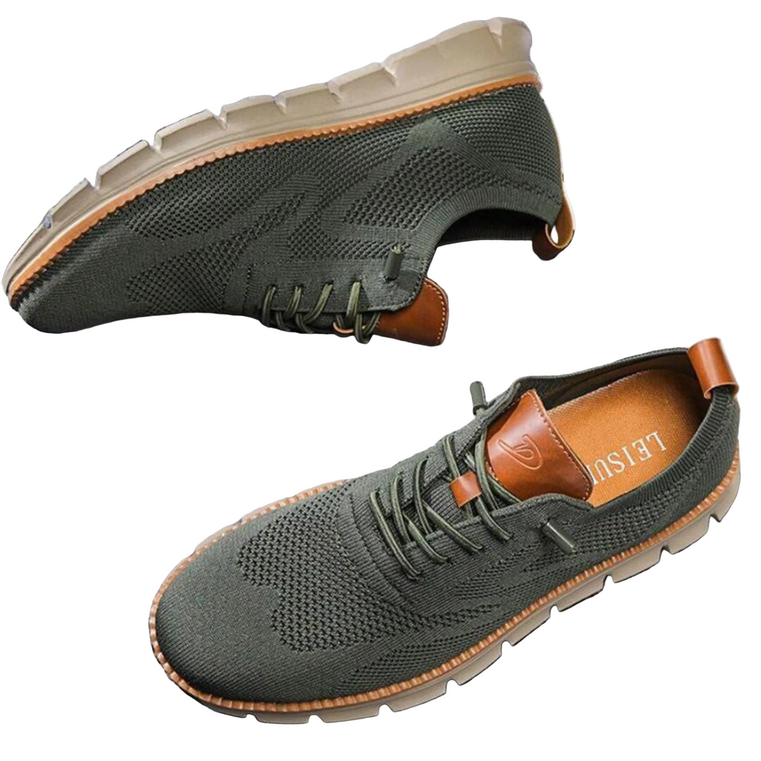 Une paire de chaussures urbaines vertes en maille respirante avec lacets, détails en similicuir camel et semelle crantée épaisse, posées sur un tapis gris.