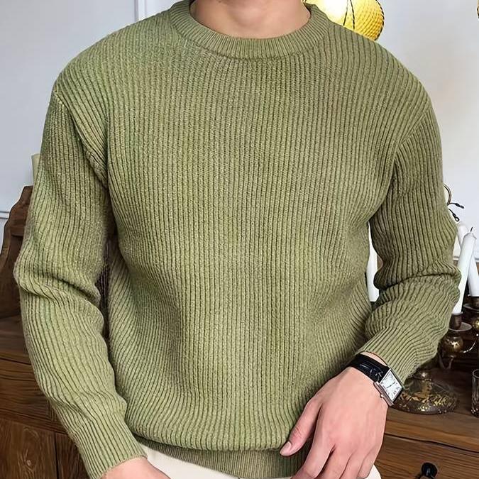 Pull classique d’hiver pour hommes  vert olive, en maille côtelée à col rond, coupe confortable avec finitions bord-côte, porté avec un pantalon clair.