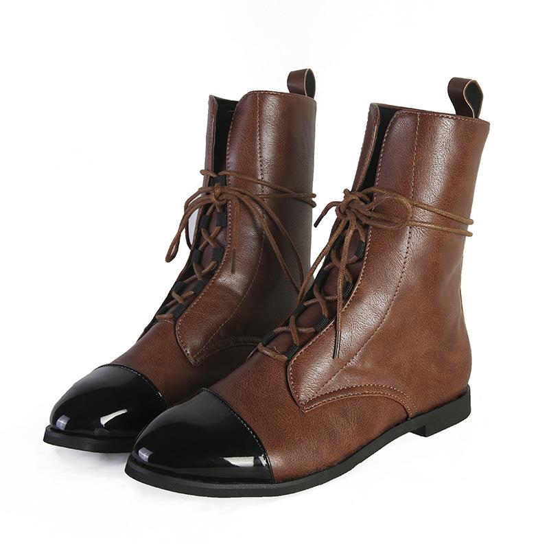 Paire de bottines cheville pour femme en cuir marron avec bouts noirs contrastants, tige mi-mollet, laçage sur le devant, finition lisse et semelle plate élégante, présentées sur fond blanc.