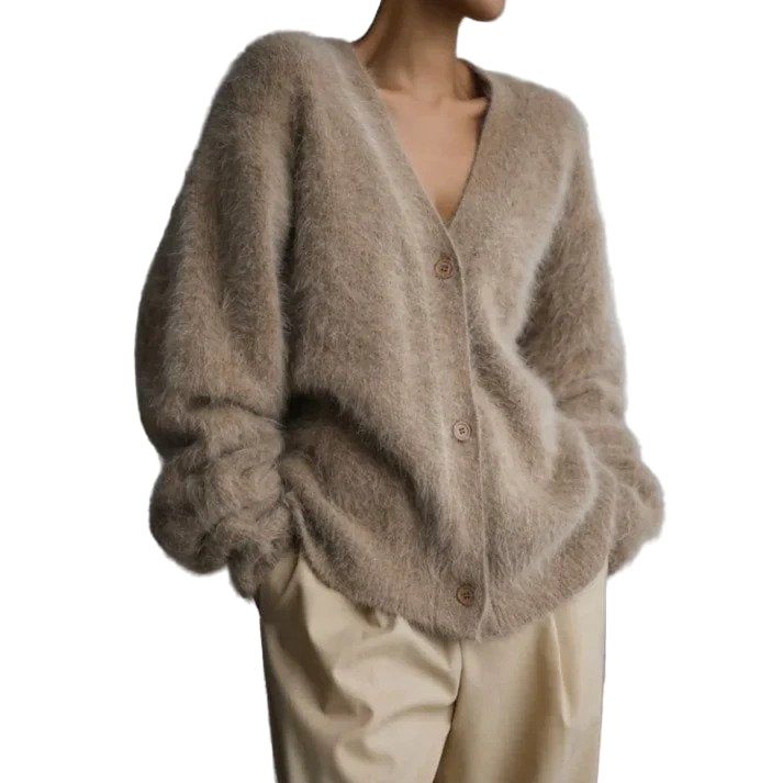Femme portant un cardigan duveteux beige à boutons, au style ample et élégant, associé à un pantalon clair, posant dans un environnement minimaliste et moderne.