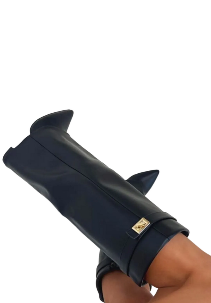 Bottes hautes noires pour femme à bout pointu, avec bride et détail métallique, portées sur fond clair.